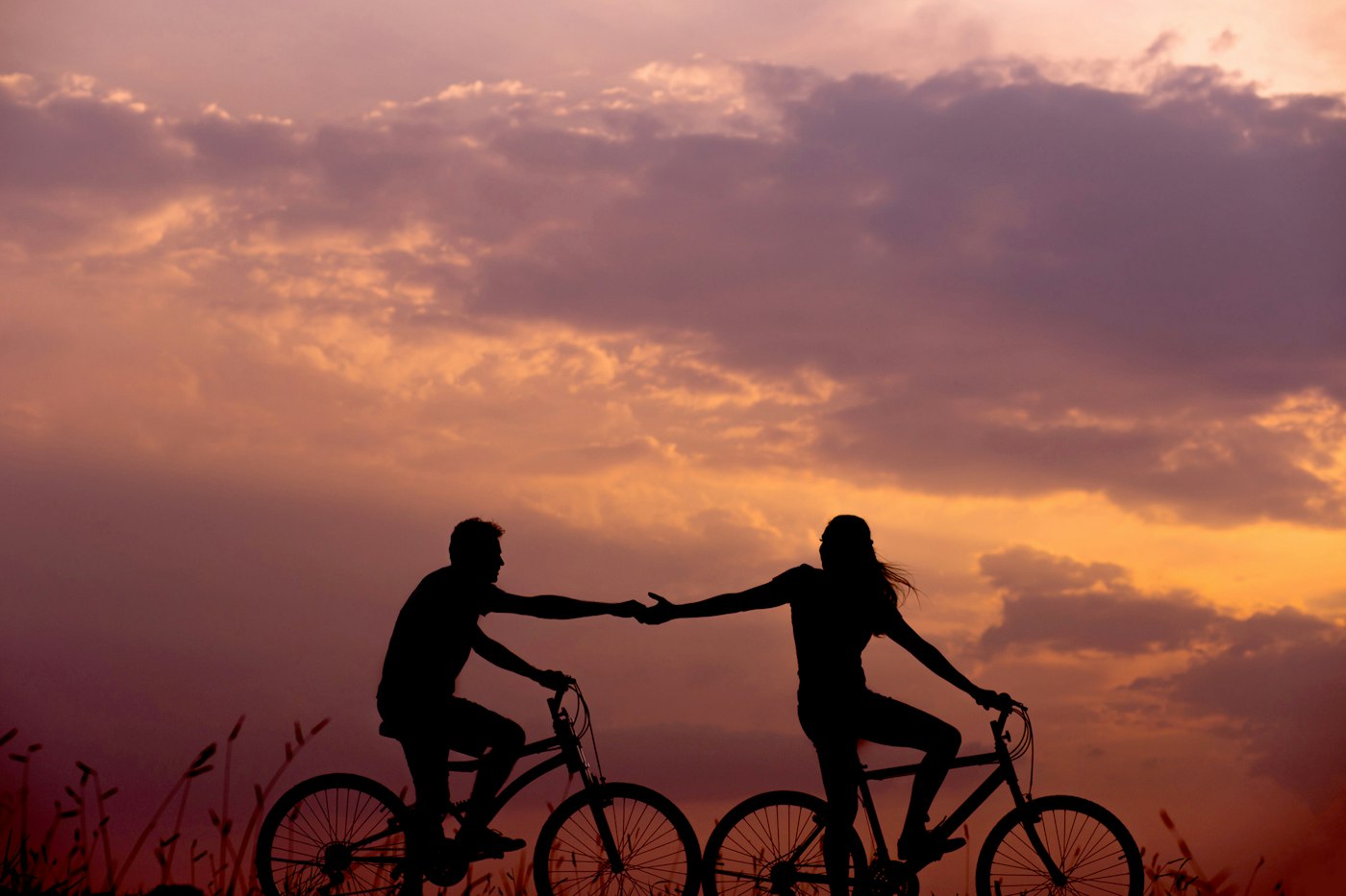 A couple riding bicycles together at sunset